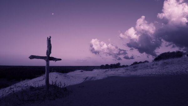A rough wooden cross on a background of purple sky and clouds